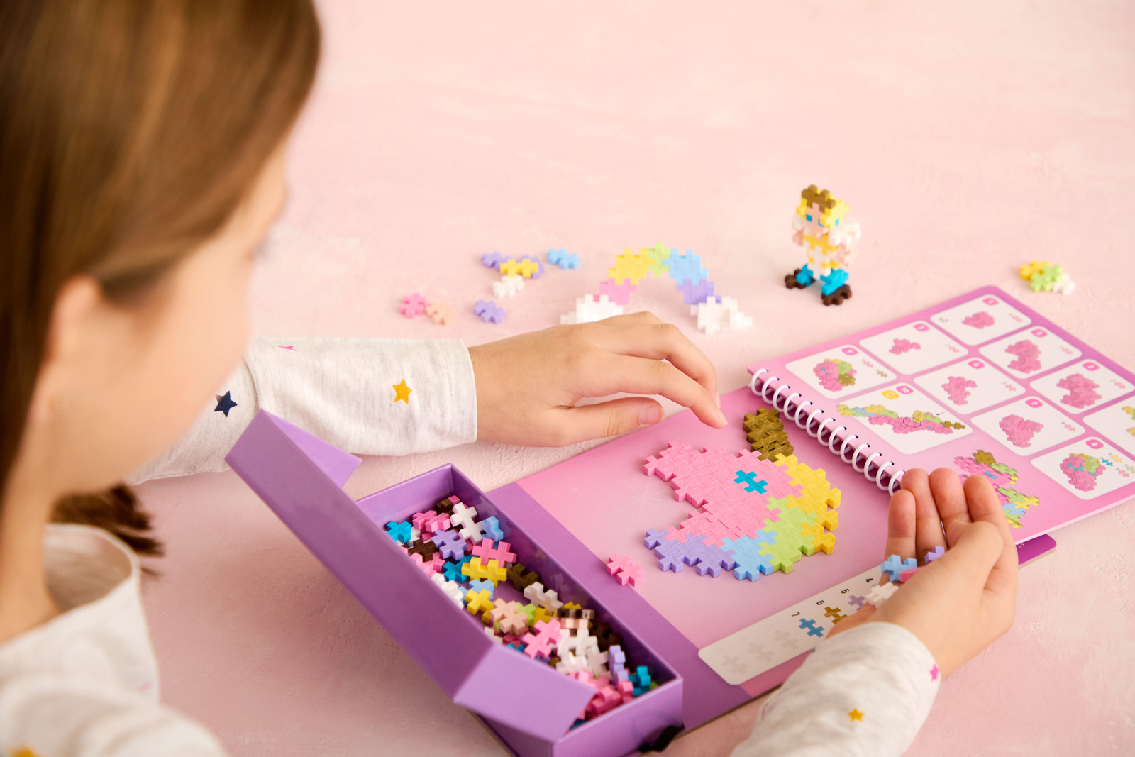 Kolorowe klocki Plus-Plus z zestawu bajkowego wysypane obok przewodnika aktywności