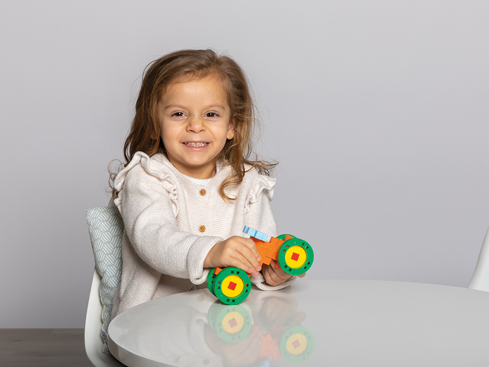 Zawartość zestawu PLUS-PLUS BIG MAKE & GO! 25 elementów ułożona obok kolorowego opakowania