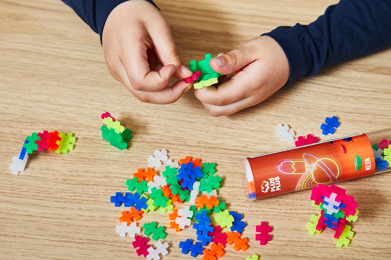 Zawartość Plus-Plus Tuba Neonowa 100 elementów wysypana obok opakowania